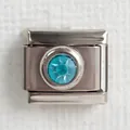 Macro shot of silver stainless steel charm with a round light blue gemstone inlay - Light Blue