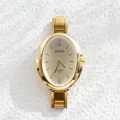 Close-up of gold oval quartz watch with champagne dial on textured white stone - Gradient Gold