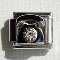Macro shot of stainless steel vintage telephone charm with black enamel and a sparkling crystal - Telephone