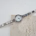Dettaglio macro dell'orologio con ciondoli in acciaio argento e pendenti a stella e torre - Quadrante Tondo Ghiera Corda Pendaglio Stella con Occhio