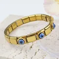 Détail du bracelet italien doré à maillons œil bleu sur un fond en pierre texturée - Œil Tacheté Or