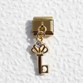 Detailed macro view of golden crown key charm with zircon on modular bracelet - Crown Key Style