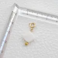 Détail d'un pendentif en nacre blanche avec fermoir doré et règle de mesure de taille - Carré