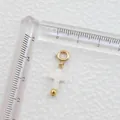 Vue macro du pendentif croix en nacre blanche avec fermoir doré et règle de mesure - Croix