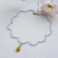 Detail von hellblauen mattierten Perlen mit gelbem Anhänger und goldener Kette - Wellenförmige blaue Perlenkette mit gelbem Anhänger (40)