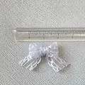 Macro d'un petit nœud en résille lilas de 3 cm avec règle pour l'échelle de taille - Mauve Clair
