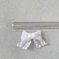 Vue macro d'un mini nœud en dentelle blanche de 3 cm pour accessoires et couture - Blanc