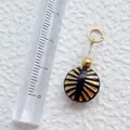 Makroaufnahme eines Vintage-Acrylanhängers mit goldenem Sonnenstrahlmuster-Detail - Schwarze Rundperle mit Sonnenstrahl-Muster (7)
