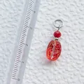 Detailaufnahme eines 22mm handgefertigten roten Acryl-Anhängers mit Linealmaßstab - Roter ovaler Anhänger mit goldener Einlage (9)