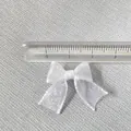 Detailed view of 30mm white organza ribbon bow measured with transparent ruler - White