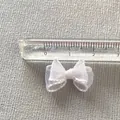 Macro view of a 2cm white organza ribbon bow accessory with a scale ruler measurement - White