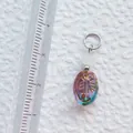 Nahaufnahme von ovalem Acryl-Anhänger mit Goldstruktur und Größenlineal zur Referenz - Ovaler schillernder Anhänger mit Pflanzenmuster (34)