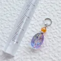 Detailaufnahme eines lila Acryl-Anhängers mit Goldglitzer und orangefarbener Perle - Violetter ovaler Anhänger mit oranger Perle (36)