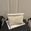 Minimalist cream faux leather shoulder bag with white sherpa trim on a leather bench - White