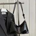 Minimalist black glossy PU leather hobo bag with knotted strap and gold hardware accents - Black