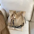 Khaki suede tote bag with golden chain strap and drawstring closure on a cozy sofa - With Pendant / Khaki