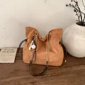 Brown suede bucket bag with gold chain strap and baseball pendant on a wooden surface - With Pendant / Brown