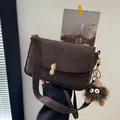 Dark brown matte shoulder bag with a gold peanut lock and fuzzy monster pendant detail - Square Bag with Monster Pendant / Coffee