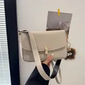 Chic cream leather crossbody bag with unique peanut buckle and plush monster charm - Square Bag with Monster Pendant / Off White