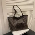 Dark brown tote bag with M letter prints and shoulder straps on a decorative book - Coffee without Pendant