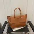 Grand sac cabas marron caramel avec motif crocodile sur une chaise noire minimaliste - Marron