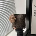 Leopard print bucket bag with dark green trim and a cute plush bear charm held by hand - With Plush Charm / Green