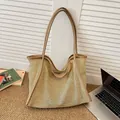 Beige gewebte Stroh-Shopper-Tasche mit braunen Ledergriffen im natürlichen Sonnenlicht - Khaki