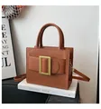 Brown faux leather crossbody bag featuring a large gold buckle and structured top handle - Brown
