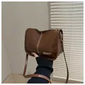 Détail du sac en cuir marron brillant avec surpiqûres en V blanches et logo en métal doré - Marron