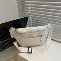 Detail of cream corduroy waist bag showing textured fabric and dual zipper pockets - White