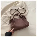 Brown faux suede handbag with a knotted handle and shoulder strap on a beige blazer - Brown