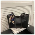 Black tote bag with white contrast stitching and a silk scarf tied on the handle - Black