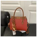 Rote Lederhandtasche mit braunem Besatz und goldenem Kirsch-Anhänger Accessoire - Rot