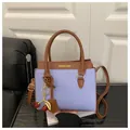 Hellviolette Handtasche aus Narbenleder mit braunem Besatz und Kirsch-Anhänger - Blau