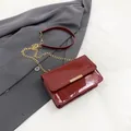 Glossy burgundy patent leather crossbody bag with gold hardware and chain strap - Red