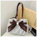 Detail van de retro stippentas met kant en een bruine leren strik voor dames - Off-wit