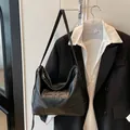 Detail der schwarzen Tote-Bag aus genarbtem Leder mit Logo auf schwarzem Blazer-Hintergrund - Schwarz