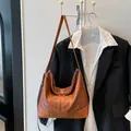 Braune Leder-Einkaufstasche mit rundem Ornament, kombiniert mit einem schwarzen Blazer - Dunkelbraun