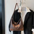 Detailansicht der großen braunen Hobo-Tasche mit Logo-Prägung und verstärkten Ecken - Kaffeebraun