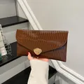 Dunkelbraune Umschlag-Clutch mit glänzender Faltenstruktur und goldenem Metallverschluss - Braun