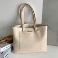 Bolso tote beige minimalista en cuero texturizado con detalles dorados y bolsillo frontal grande - Blanco