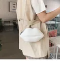Close-up of white glossy lip-shaped crossbody bag with gold metal chain strap on model - White