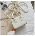 Detailed view of mini white leather crossbody handbag held against a beige blazer - White