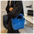 Detail of bright blue corduroy bucket bag with adjustable strap and white button snap - Blue