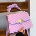 Detail of lavender quilted bag with heart-shaped gold clasp and ruched handle texture - Purple