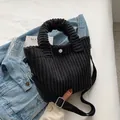Black corduroy bucket bag with vertical texture, white button, and adjustable strap - Black