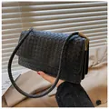 Detailaufnahme der schwarzen gewebten Lederhandtasche mit goldenen Metallteilen - Schwarz