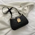 Bolso de hombro acolchado negro con cierre dorado sobre un blazer blanco - Negro
