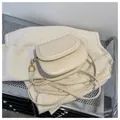 Detailansicht der cremeweißen Satteltasche mit den goldenen Metallhaken der Träger - Weiß
