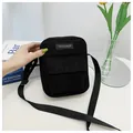Detail of black corduroy crossbody bag featuring a front pocket and adjustable strap - Black